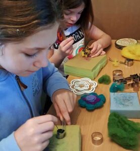 Two children learning to needle felt safely